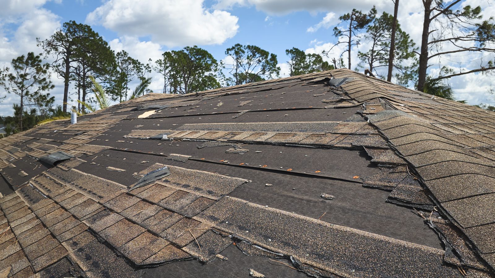 Damaged house roof with missing shingles after a storm