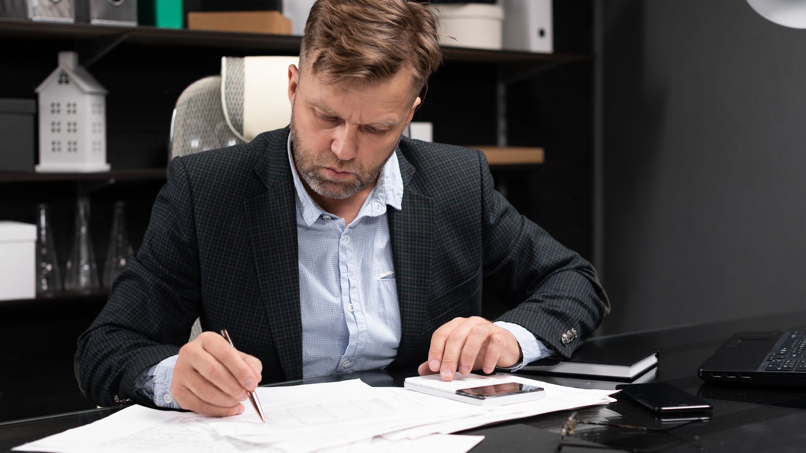 Man reviewing papers and using a calculator at a desk