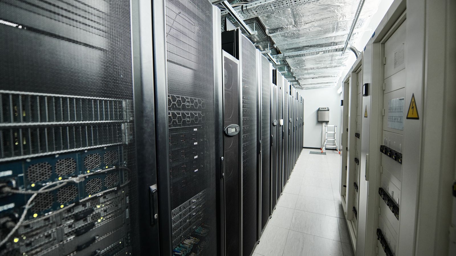 Narrow aisle between rows of server racks in a data centre