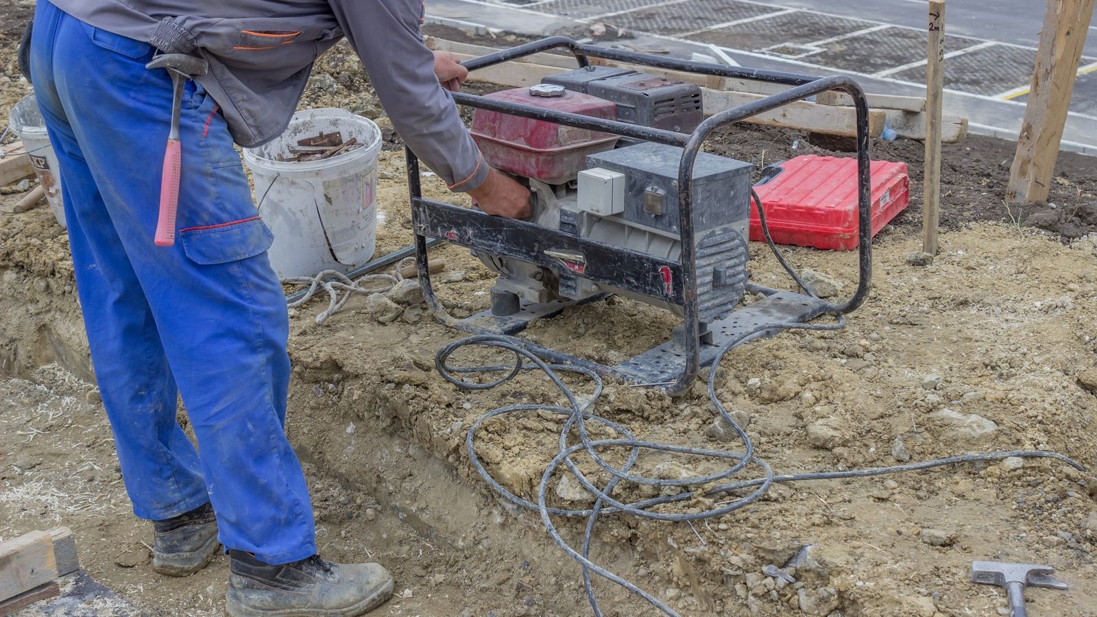 Worker operating a portable generator on a muddy construction site