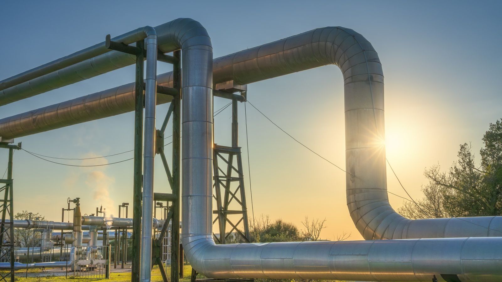 Large steel pipeline loops at an industrial site at sunrise