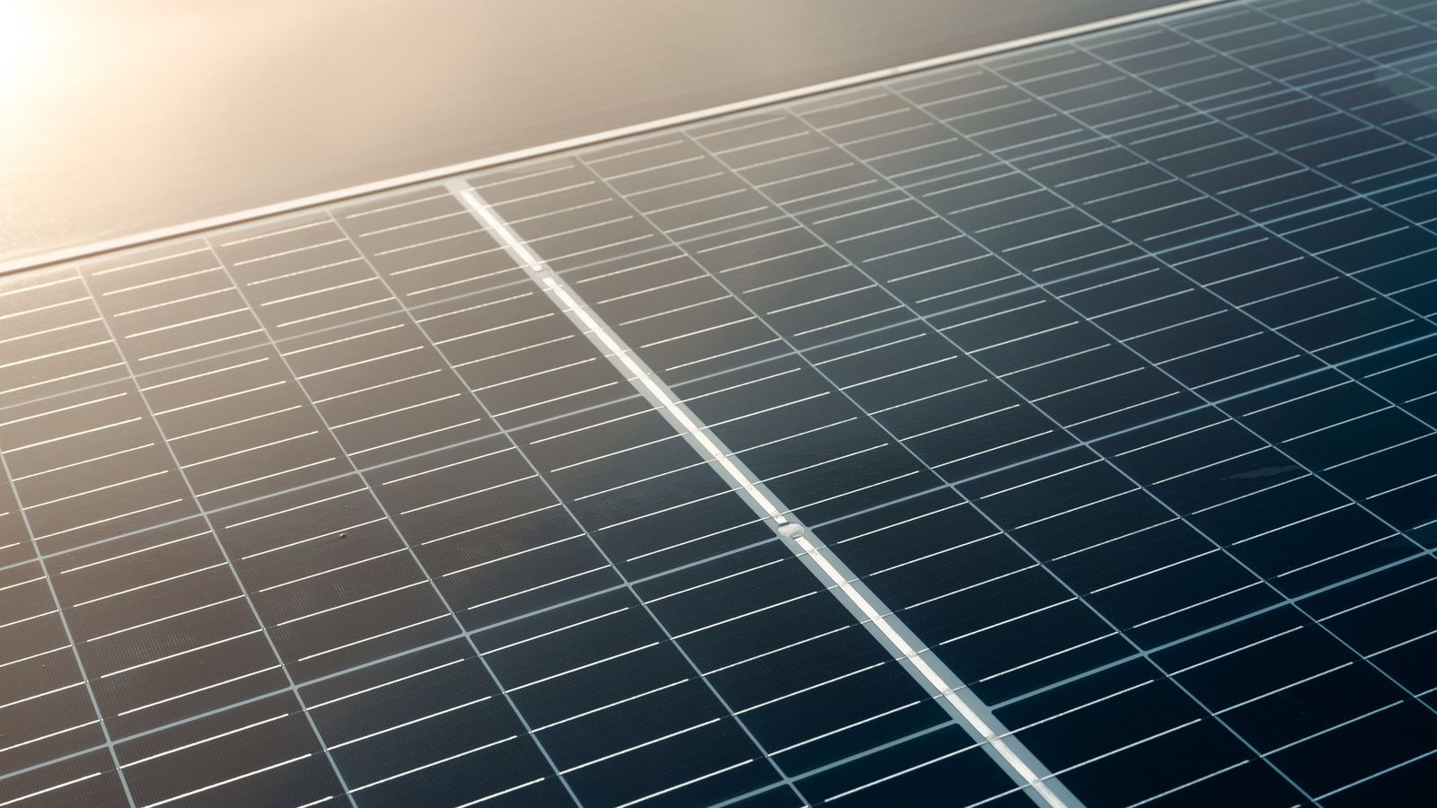 Close-up of a solar panel surface with cells and frame catching the light