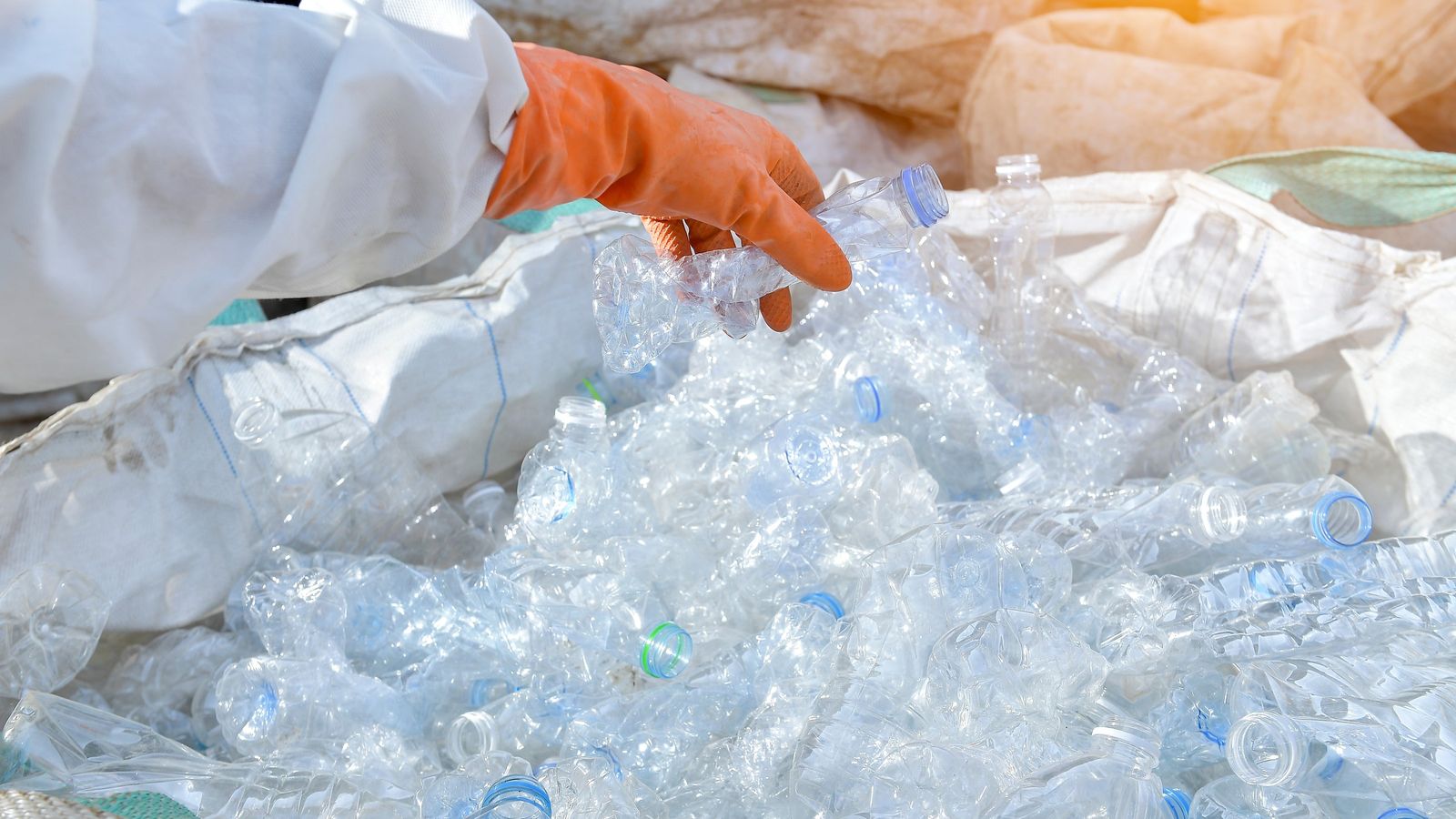 Heap of empty plastic bottles being sorted by a gloved hand