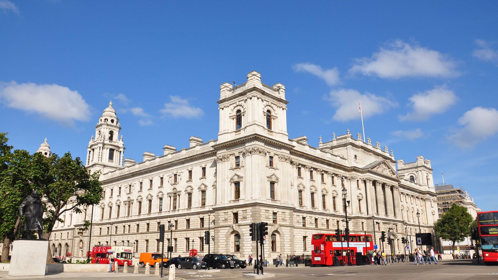 Grand government office building in Westminster with red buses passing