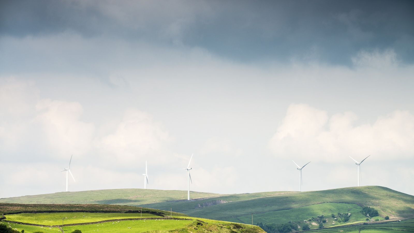 Wind turbines on the skyline above green rolling moorland hills